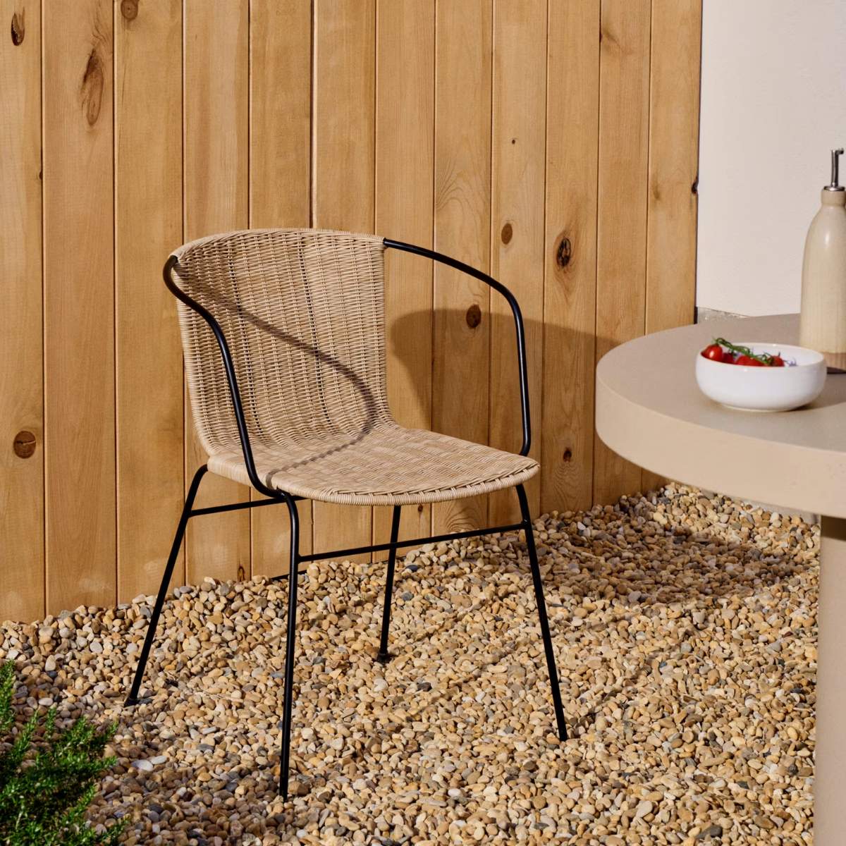 Kave Home Eltiera stackable chair in synthetic rattan with black steel frame and armrests