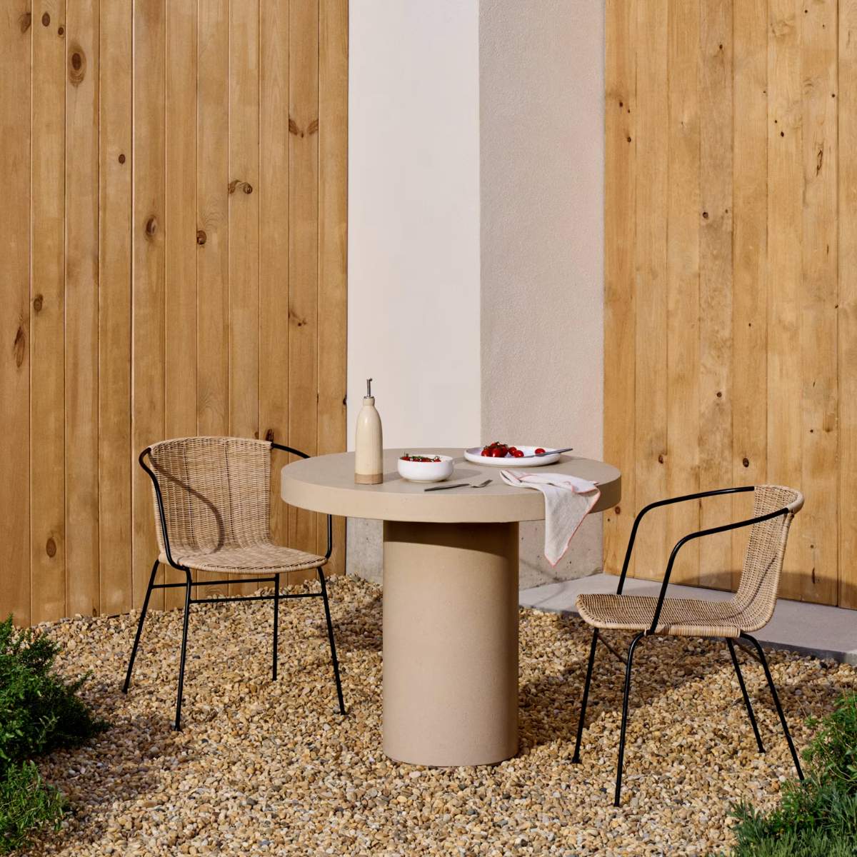 Kave Home Eltiera stackable chair in synthetic rattan with black steel frame and armrests